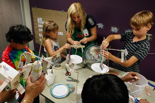 Austin Children's Museum volunteer Alyssa Guiliani helps kids finish their kinetic energy projects at a Secret Scientists summer camp in Austin on June 27, 2012.