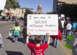 A kindergarten-age schoolboy walks up Congress Ave for a Save our School's rally on February 23rd, 2013