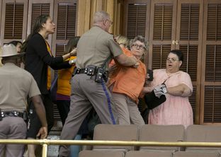 A woman in the Senate gallery pushes back against a police officer and is later arrested during the last hour of the Senate session on June 25, 2013.