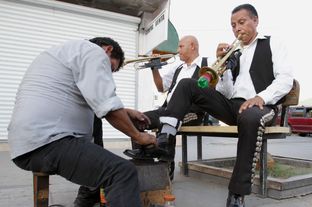 Ignacio Villa, left, and Arturo Ibarra, right, of the mariachi group Los Gavilanes receive shoe shines on Avenida Juárez in Ciudad Juárez, México, Jul. 9, 2013.
