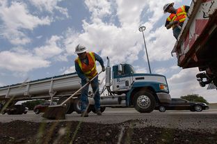 TxDOT employees Brad Shepard and Canaan Johnson finish up after putting asphalt cold mix down for edge repairs on Interstate 35-S near Parmer Lane on Monday August 19th, 2013.