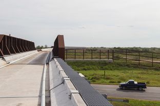 The uncompleted new international railroad bridge near Brownsville passes over the border fence and US 281 before crossing the Rio Grande.