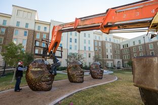 Michael Stutz, a sculptor from San Diego, California, assists members of his team in installing his new creation, Four Faces, at Texas Tech University's Talkington Hall.