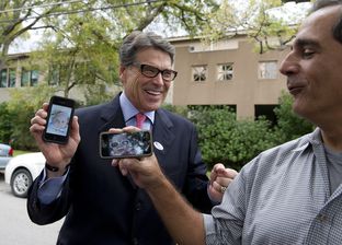 Gov. Rick Perry shows a picture of his new granddaughter to a reporter after voting early in Austin on Oct. 30, 2013.