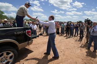 Lt. Gov. David Dewhurst accepted the microphone from Texas landowner Tommy Henderson on April 28, 2014, during a gathering of politicians, landowners, law enforcement officials and news outlets on Red River land northeast of Byers, Texas. Dewhurst expressed support for ranchers in their fight with the BLM over land they say they own.