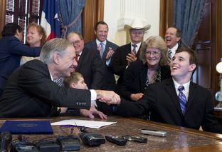 Gov. Greg Abbott, l, shakes hands with student Zachariah Moccia, 25, of San Antonio after signing SB 339, allowing limited medical use of marijuana-derived oils that help control seizures in epileptic patients on June 1, 2015.