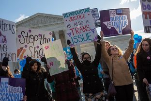 Protesters hold signs in front of the U.S. Supreme Court in Washington, D.C. as Whole Woman’s Health v. Hellerstedt is argued inside.