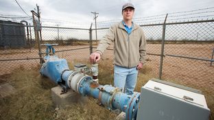 Kyle Krueger, a staff engineer with the Colorado River Municipal Water District, stands next to an older water well on land acquired through state financing near Wickett, Texas.