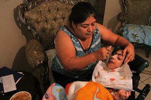 Maria Figueroa feeds Antonio Fuentes, 28, who has cerebral palsy and cannot speak. Figueroa has been Fuentes' health care provider for the past eight years.