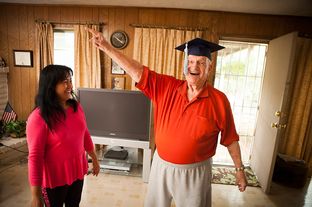 Robert Titus tries on his graduation cap with the help of his wife, Jennifer, in his Houston home on Nov. 26, 2012. Titus recently earned an online degree in marketing managment from WGU Texas.