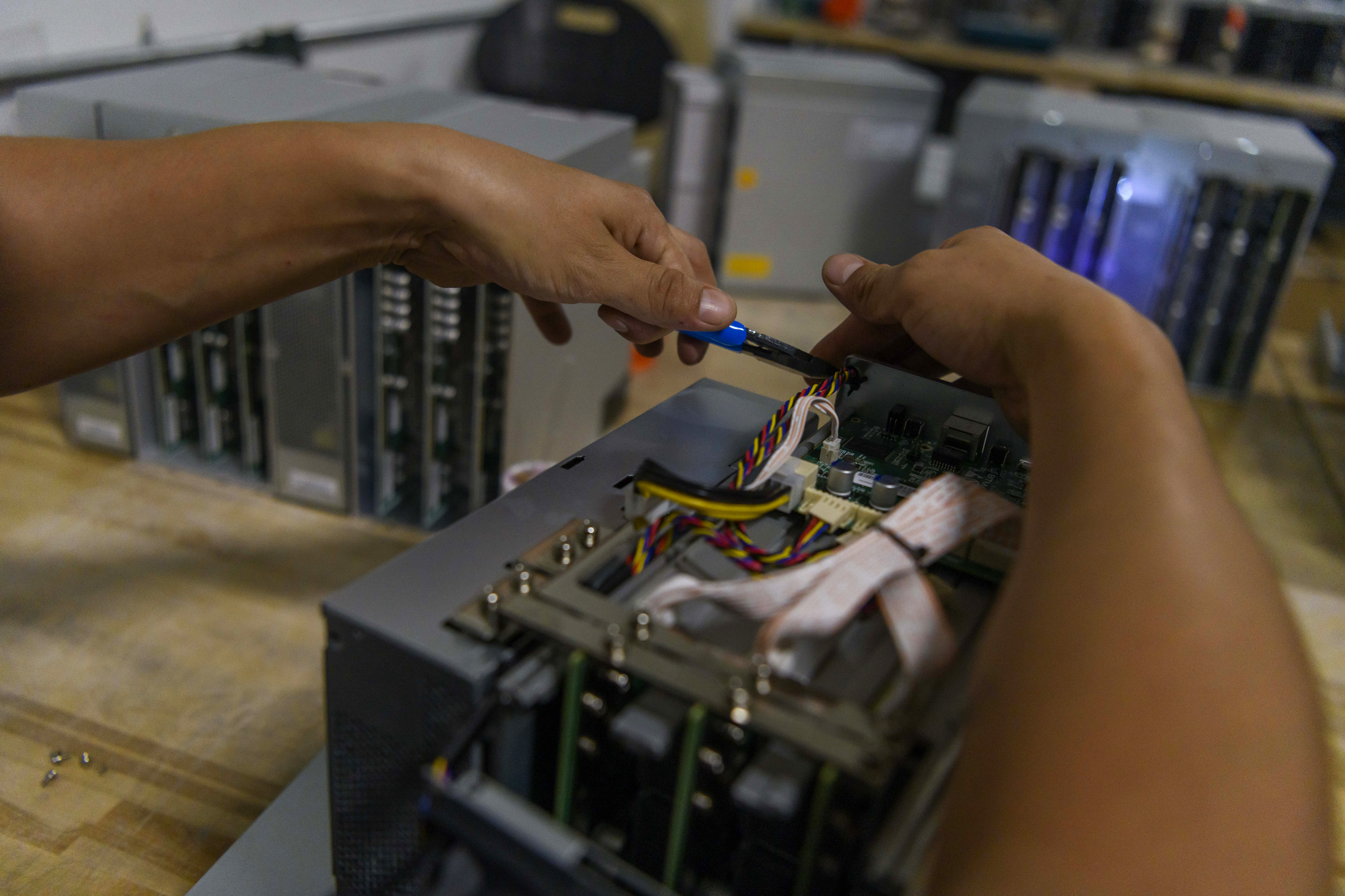 A Helios employee takes apart ASIC mining servers, computers deployed to mine Bitcoin, and gets them ready to be installed into the pods, near Afton on Sept. 15, 2022.