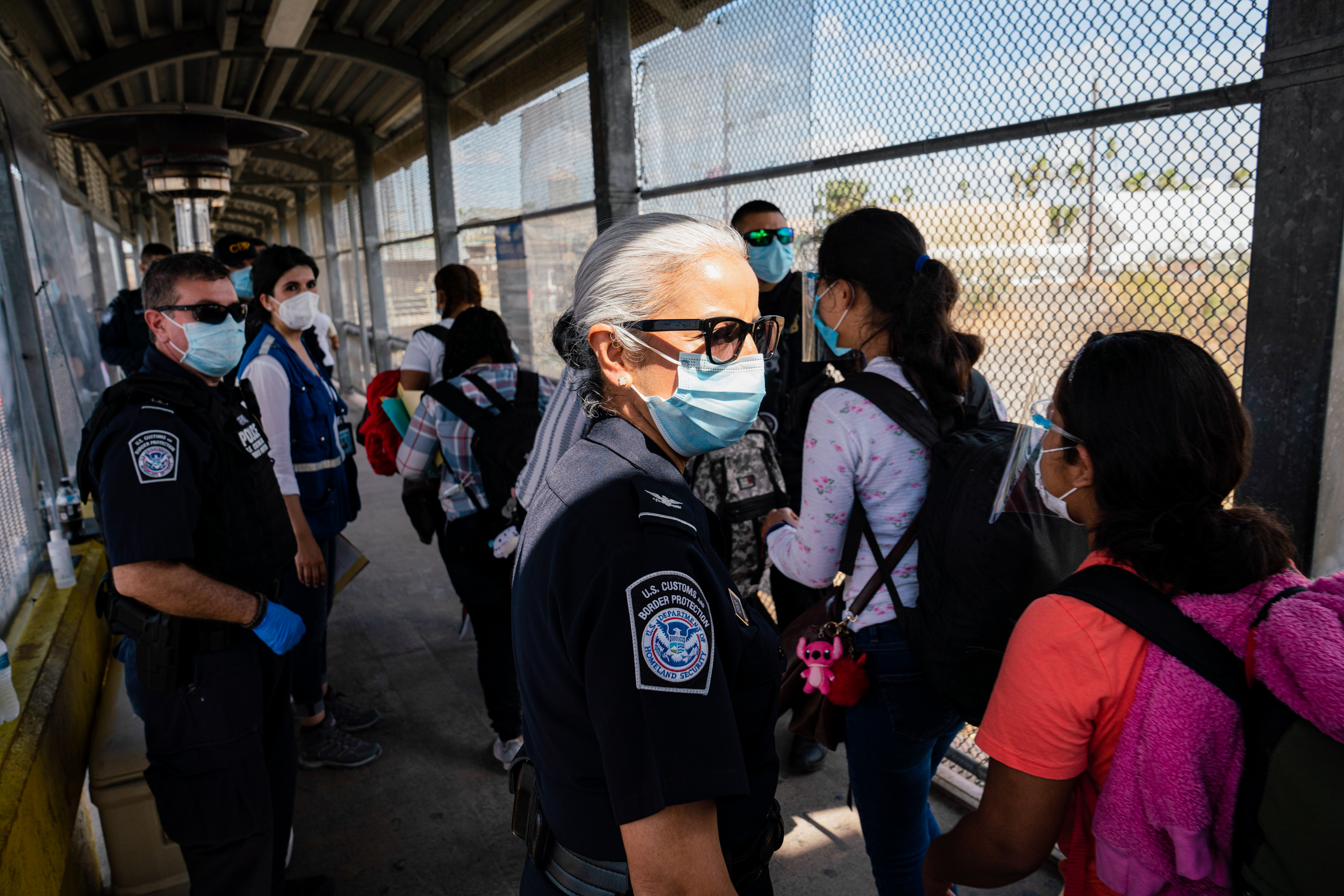 Asylum seekers wearing face shields make their way to be processed in the U.S. at the Gateway International Bridge in Matamoros, Mexico on Feb. 26, 2021.