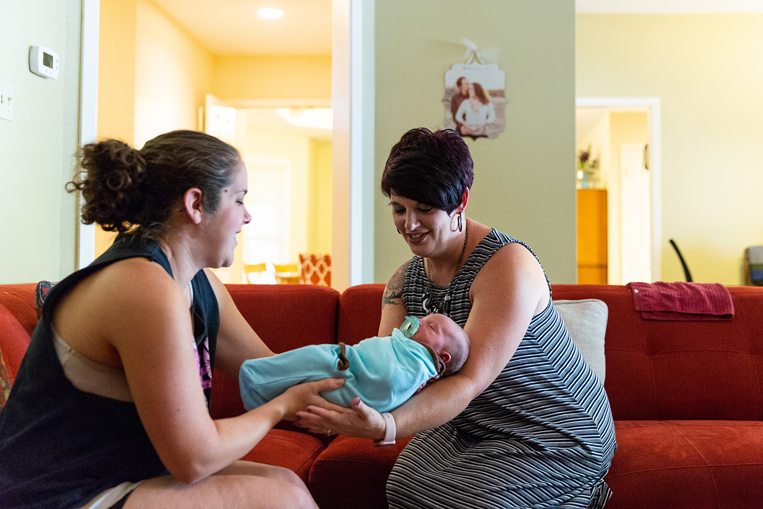 Hailey Frazier (left) gives her son Isaac to Sabrina Elliott (right), a doula in Abilene during a home visit.