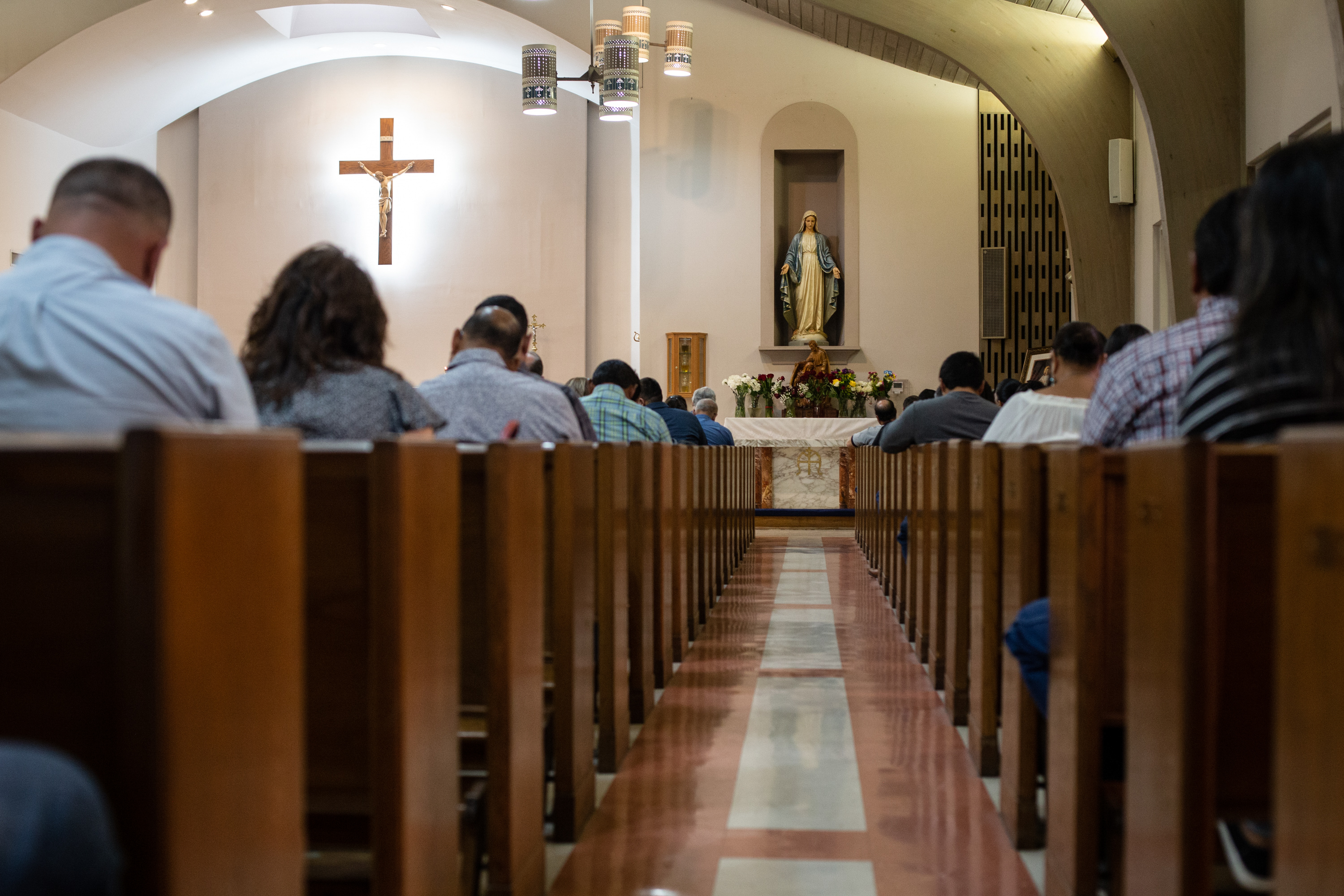 Churchgoers bow their heads in prayer during mass at the Sacred Heart Church in Uvalde on May 29, 2022.