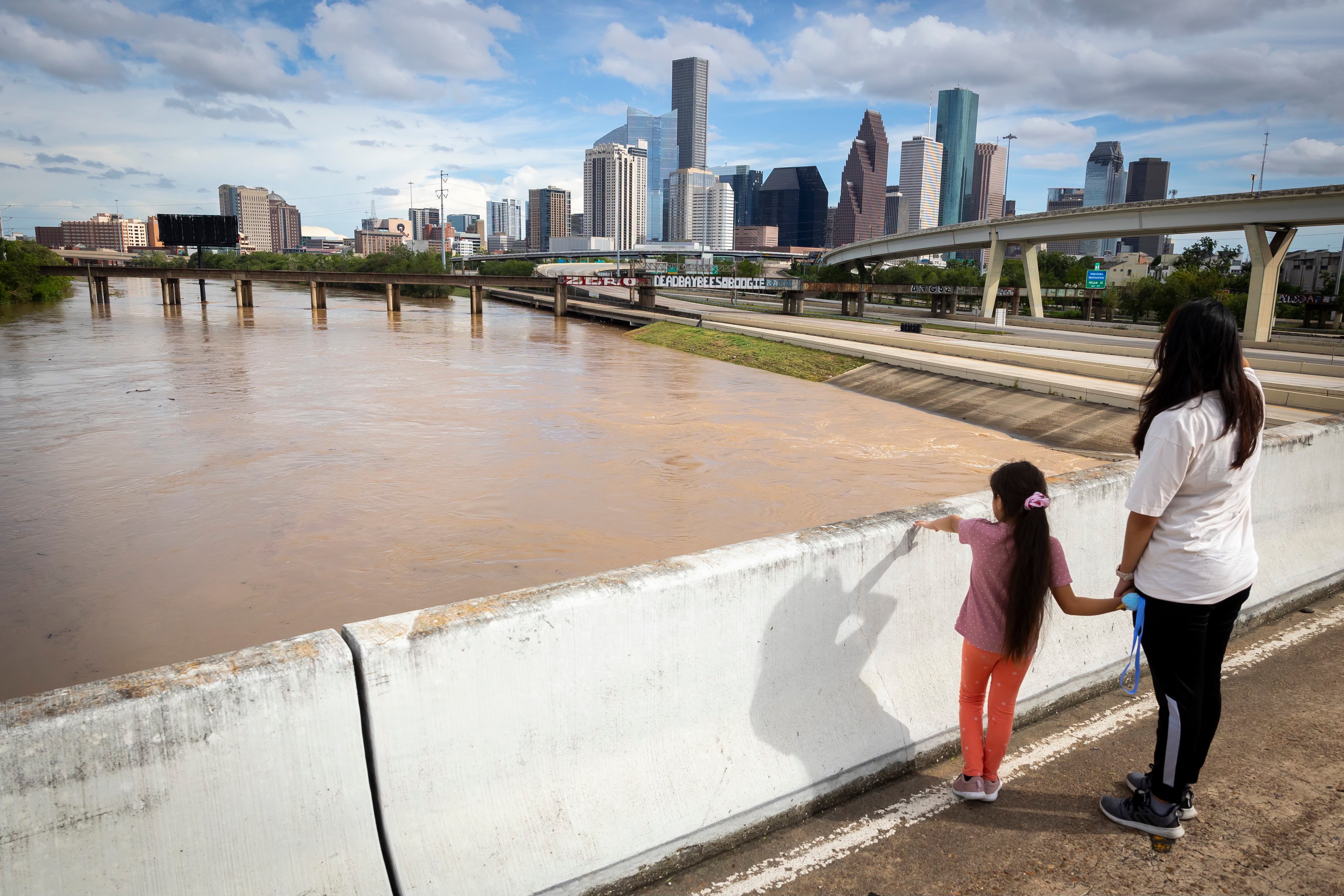 Two sisters watch flooded Whiteoak Bayou waters flow next to downtown Houston on Monday, July 8, 2024. Rains from Hurricane Beryl overflowed the bayou but were not as significant as Hurricane Harvey.