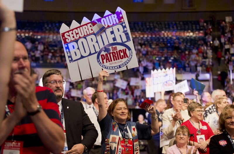 Delegates wave Dan Patrick posters advocating a more secure border on the Texas Republican Convention floor on June 7, 2014.