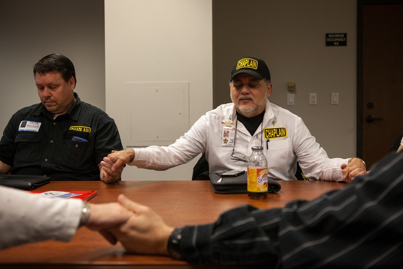 Michael Tummillo (right), the official volunteer chaplain at the Texas Department of Agriculture, joins hands in prayer with attendees at a weekly "Faith at Work" gathering at the Stephen F. Austin state office building.