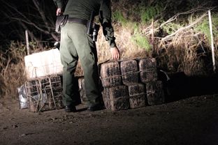 After chasing away the smugglers using rafts to bring drugs across the river, Border Patrol and Texas DPS agents inspect several large packages of marijuana abandoned near the Rio Grande shoreline near Roma, Texas, on March 8, 2016. The packages were later found to weigh 313 pounds, making them worth an estimated $240,000.