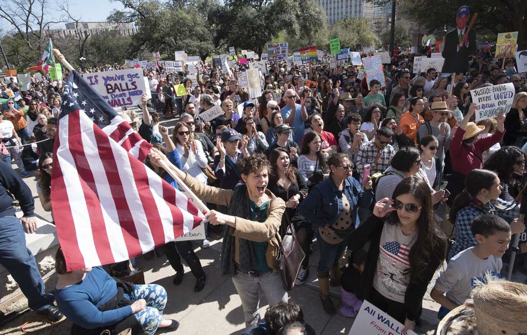 Dorothy Kuhn waves the American flag before thousands gathered at the South Steps of the Texas Capitol on Feb. 25, 2017 for a #NoBanNoWall rally decrying Trump's immigration policies.