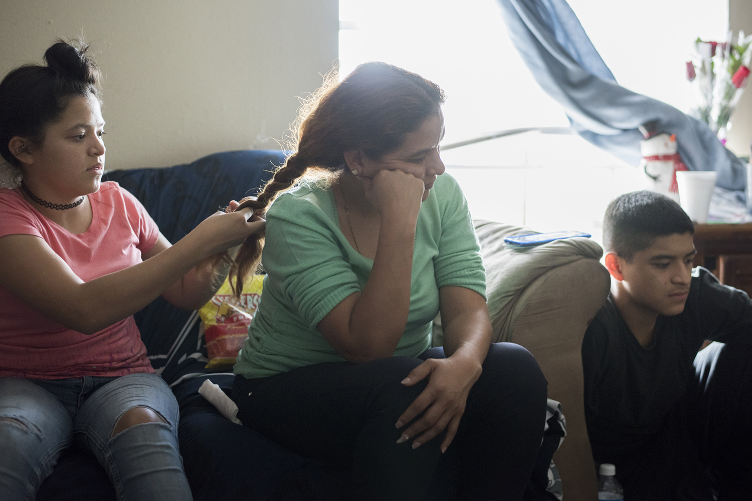 Rosa Ortega looks at her son Rene Garza, 16, while her daughter Gracie Garza, 12, braids her hair in Grand Prairie. 