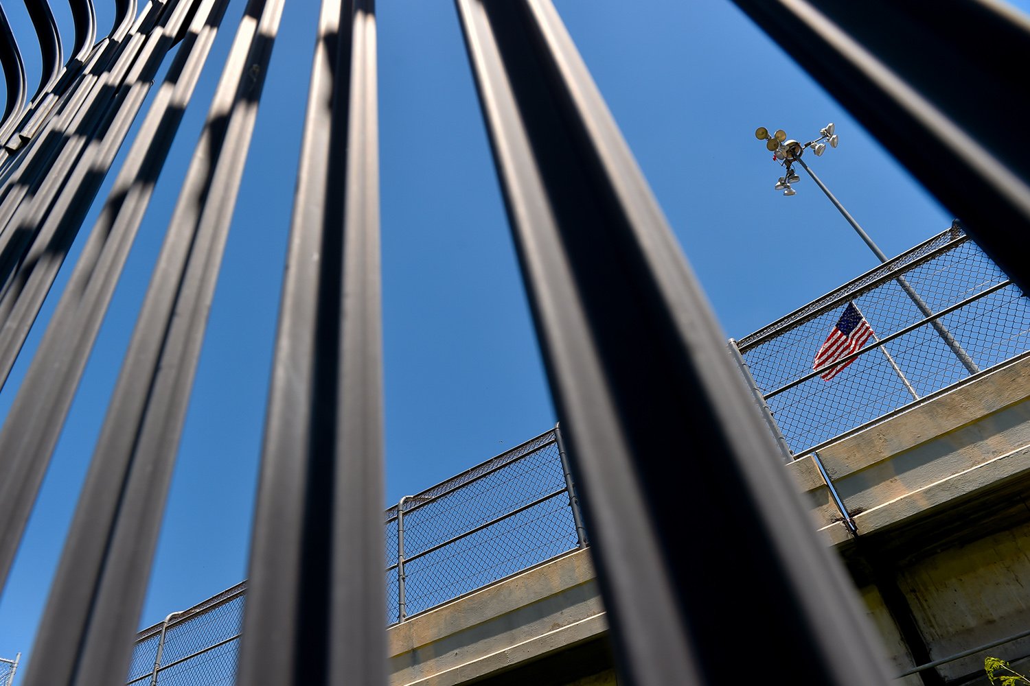 An American flag flies over the international bridge at Eagle Pass, seen through the border fence.