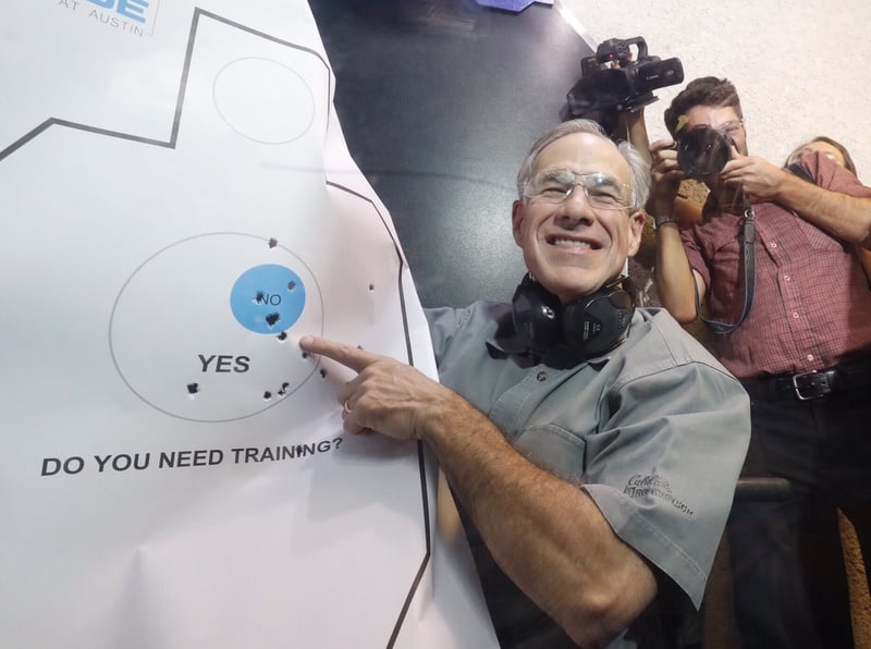 Gov. Abbott admires his practice target after signing Senate Bill 16, which reduces the first-time fee for a license to carry handguns, on May 26, 2017.