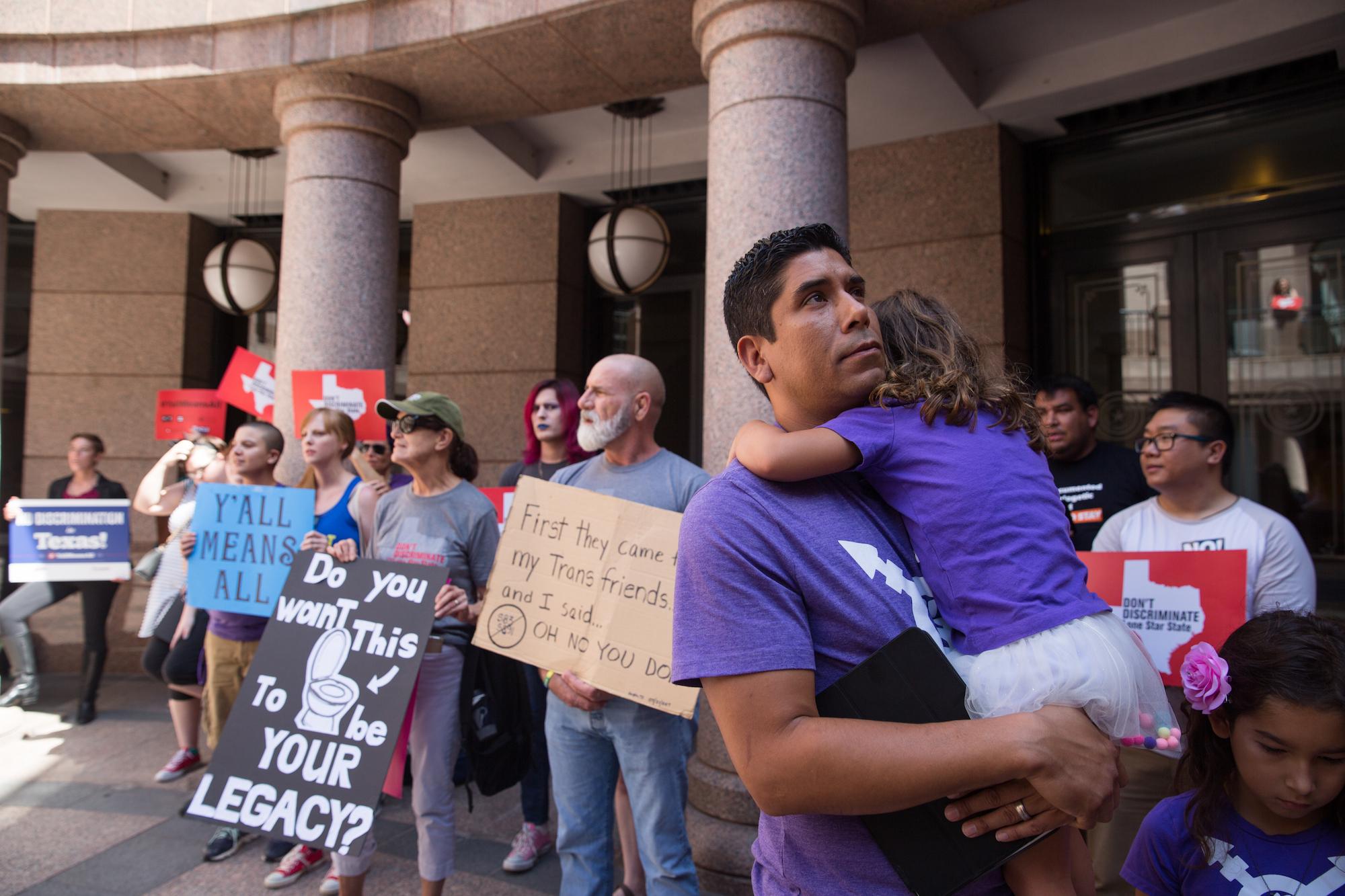 Frank Gonzales holds his daughter after speaking at a rally to denounce bathroom restrictions for transgender Texans on July 21, 2017.