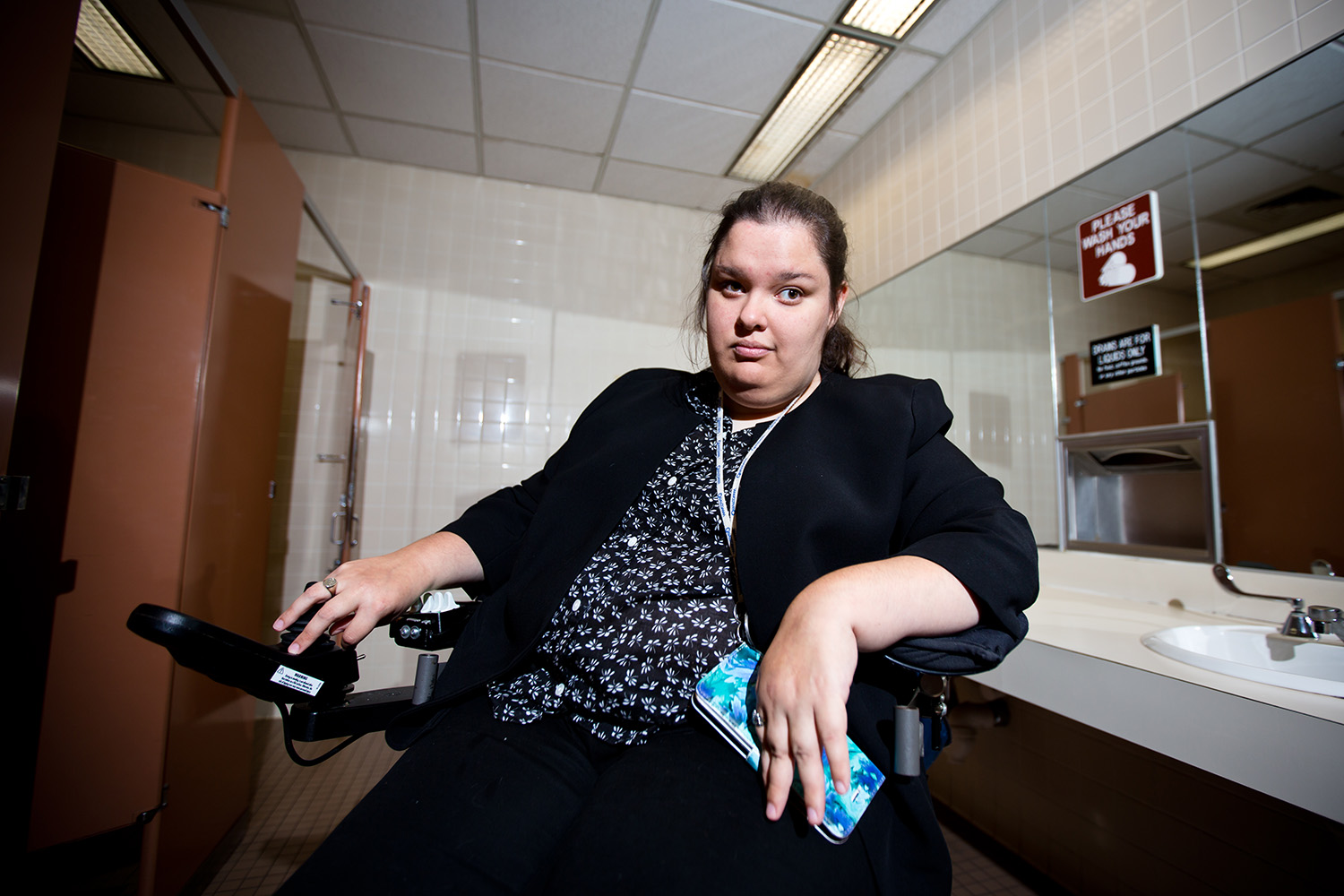 Amy Litzinger poses outside of a bathroom stall that's too small for her and her attendant. Litzinger, along with many other disabled Texans, is concerned about the implications a 