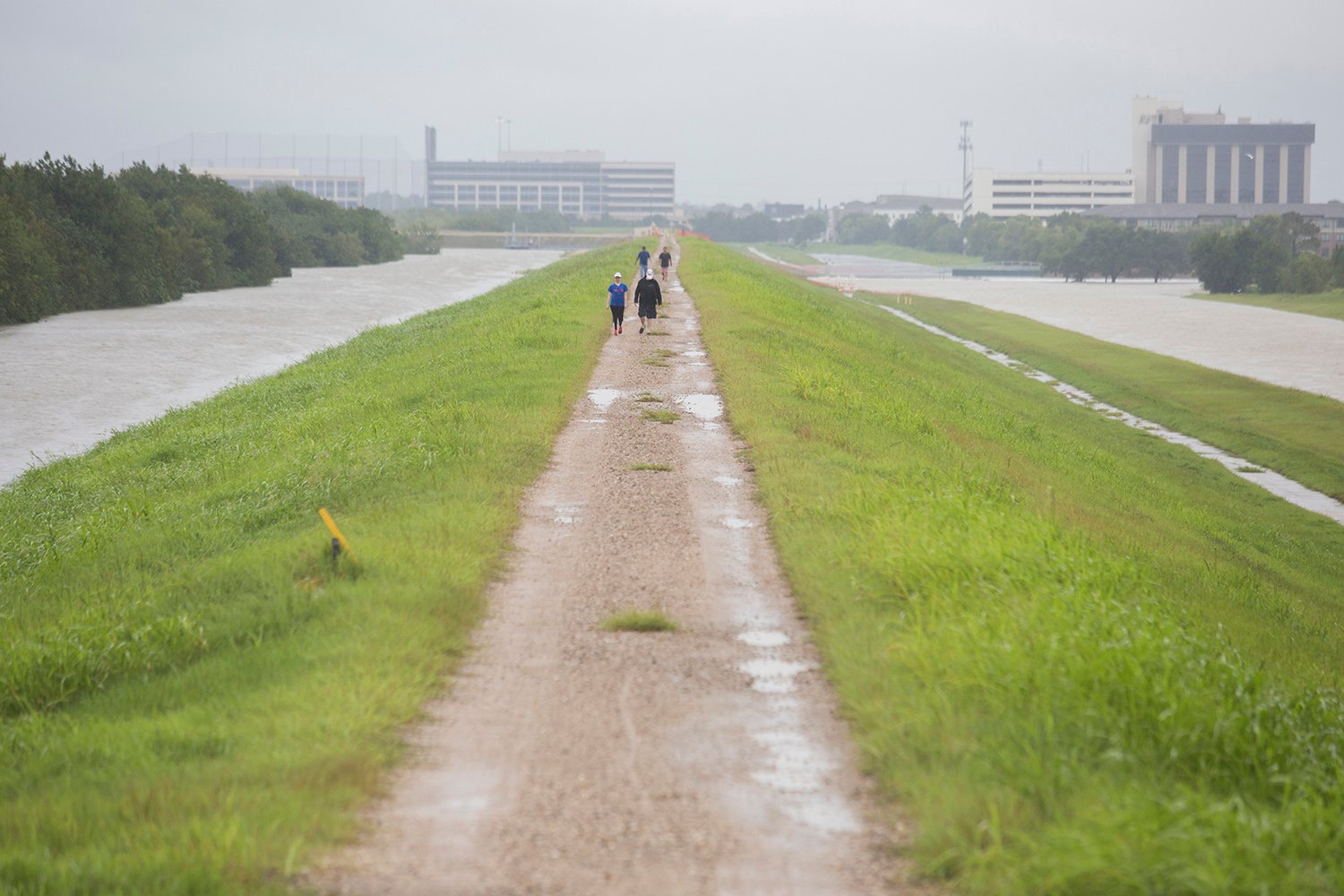 People walk along the Barker Reservoir Dam in Houston on Tuesday, Aug 29, 2017. Torrential rains from Hurricane Harvey caused the U.S. Army Corps of Engineers to release water from the reservoir, aggravating flooding in neighborhoods below the dam.