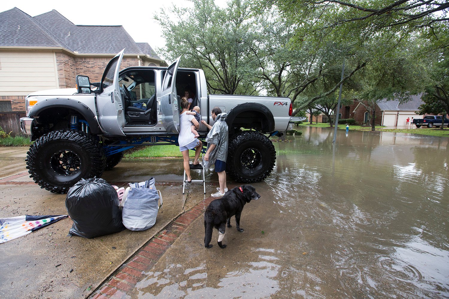 Chris Ginter, right, helps a family into his truck in Houston on Tuesday, Aug. 29, 2017. Ginter is helping evacuate people from their flooded neighborhood near Buffalo Bayou.