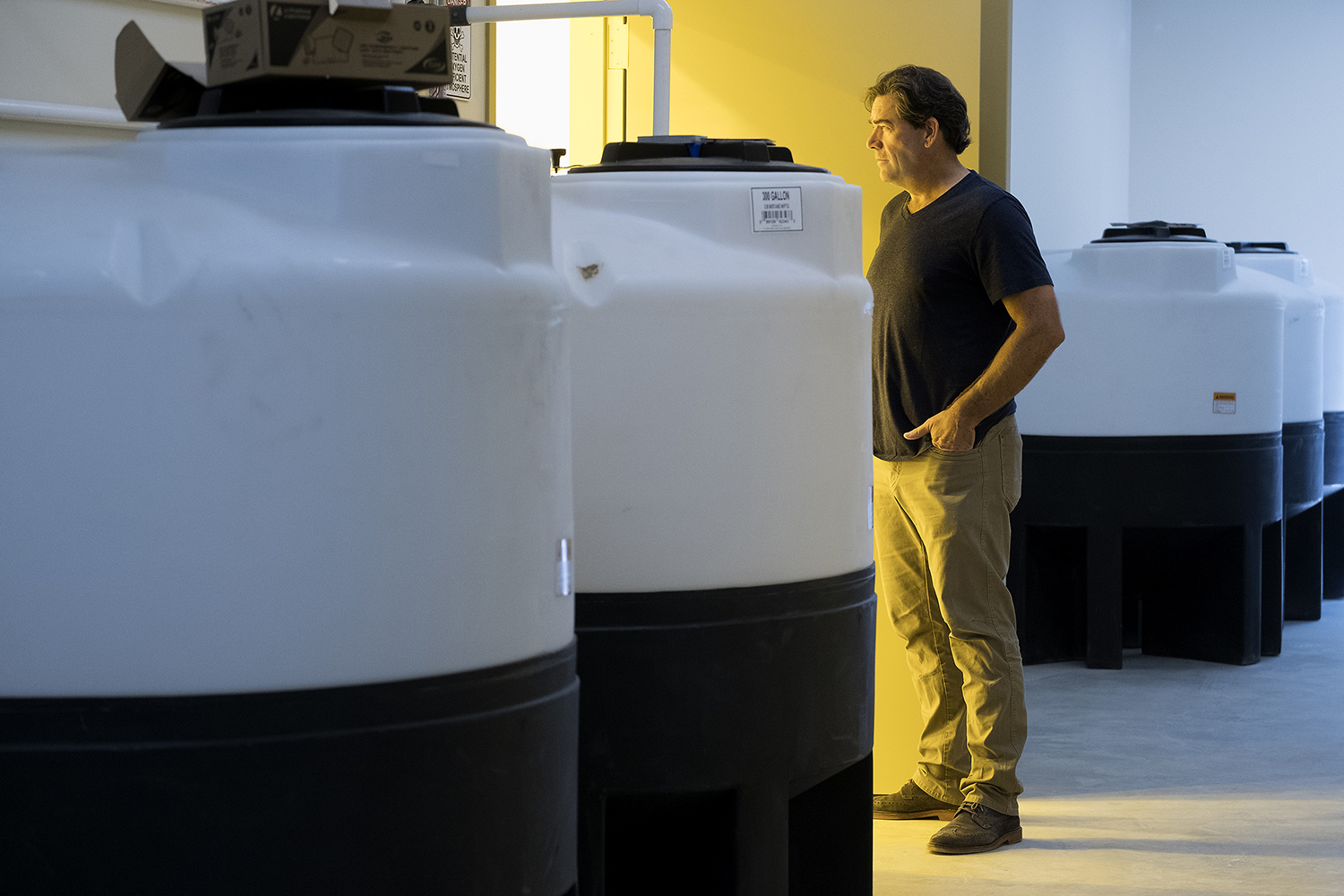 Surrounded by fertigation tanks, Compassionate Cultivation CEO Morris Denton looks into a vegetation room where marijuana plants will begin their growth process. 